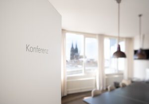 Heller Konferenzraum mit großem Tisch und Blick auf den Kölner Dom im Hintergrund