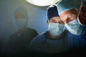 Nahaufnahme von zwei Operateuren mit Mundschutz und Haube im Operationssaal