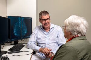 Arzt bespricht Mammographie-Befund mit älterer Patientin in vertrauensvoller Atmosphäre